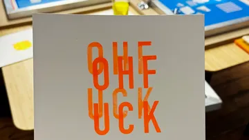 Card with overlapping orange text on table.