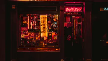 Neon-Whiskey-Schild vor schummrigem Laden.
