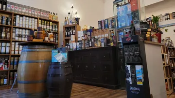 Whiskey store with bottles on shelves and barrels.