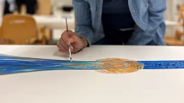 Person painting abstract design on canvas.