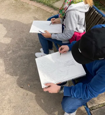 Two people sketching trees on large pads.