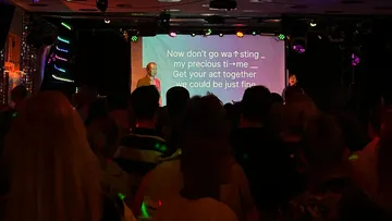 Publikum sieht Karaoke mit projizierten Texten.