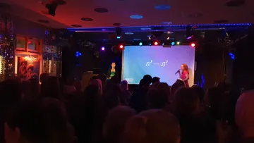 Zwei Personen singen bei Karaoke-Nacht auf der Bühne.