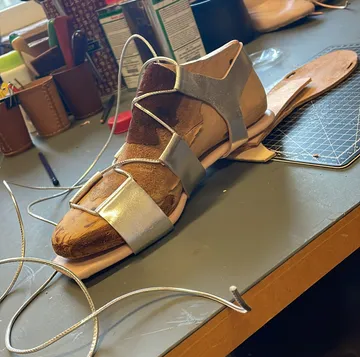 Unfinished sandal on a cluttered workbench.