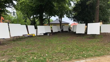 Blank canvases on stands in a park.