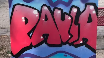 Red graffiti text on urban wall.
