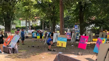 Children painting on easels in a park.