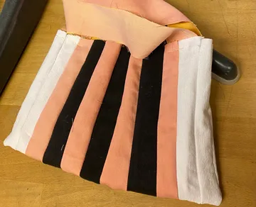 Gestreifte Tasche wird auf Tisch gefertigt.