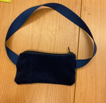 Blaue Tasche mit Band auf Holzoberfläche.