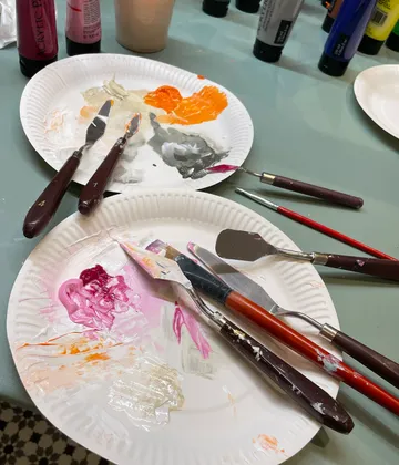 Palette knives with paint on paper plates.
