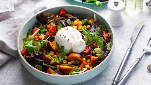 Fresh salad with burrata in a bowl.