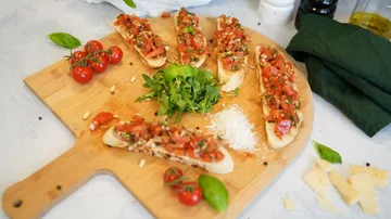 Bruschetta on wooden board with ingredients around.