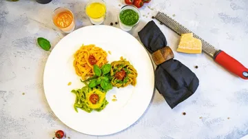 Three pasta varieties on a plate, sauces nearby.