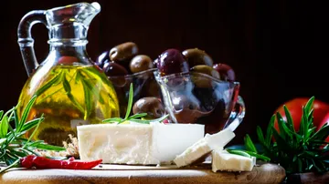 Cheese, olives, oil on wooden board.