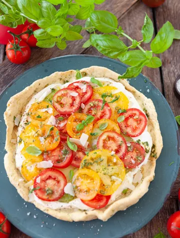 Tomato tart with basil on wooden table.