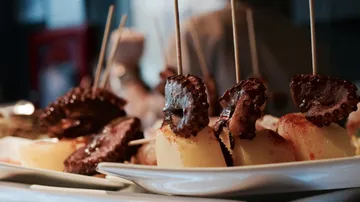 Octopus and potatoes skewers on plates.