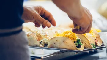 Hands assembling tacos at a kitchen counter.