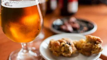 Beer glass beside plate of snacks.