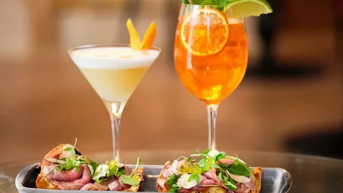 Zwei Cocktails und Vorspeisen auf einem Tisch.