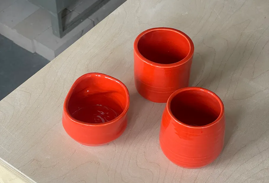 Drei rote Keramikbecher auf Holzoberfläche.