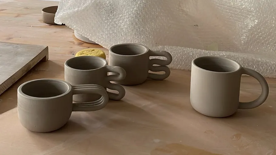 Tonbecher mit einzigartigen Griffen auf Holztisch.