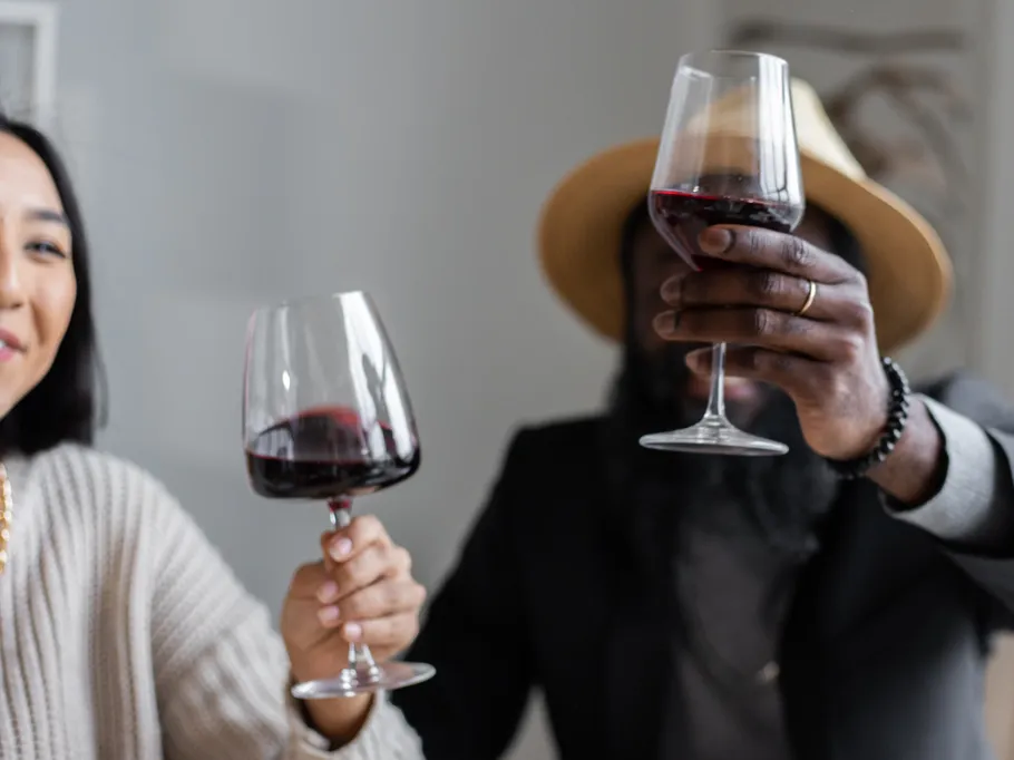 Two people toast with red wine in glasses.