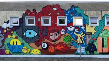 Bunte Graffiti bedecken eine Wand mit Fenstern.