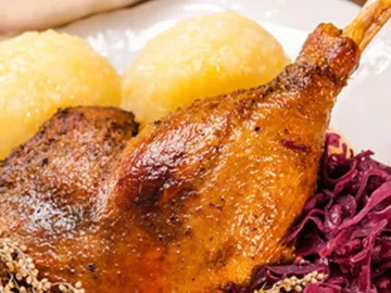 Chicken leg lies on a plate with side dishes.