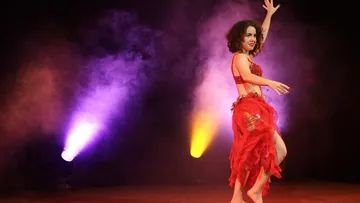 Dancer performing on stage with colorful lights.
