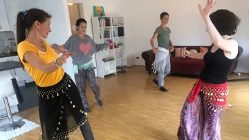 Vier Frauen tanzen energetisch im Wohnzimmer.