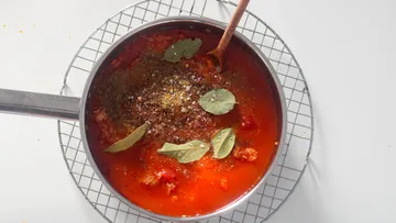 Tomato sauce simmering in a pot with spices.