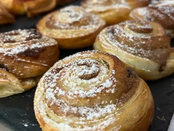 Gebäck mit Puderzucker auf dunklem Tablett.