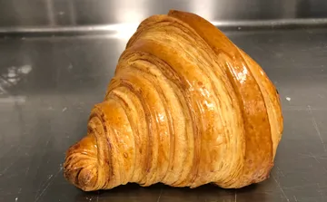 Goldenes Croissant auf Edelstahlfläche.