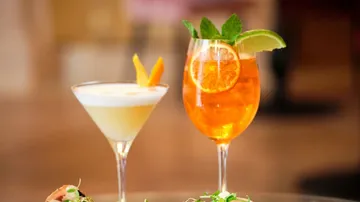 Two cocktails with lemon and mint garnishes.