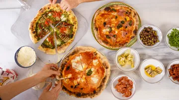 Drei Pizzen mit Belägen auf Marmortisch.