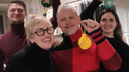 Vier lächelnde Personen halten Ornamente drinnen.