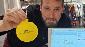 Mann hält gelbes Objekt nahe Tablet, Bekleidungsgeschäft.