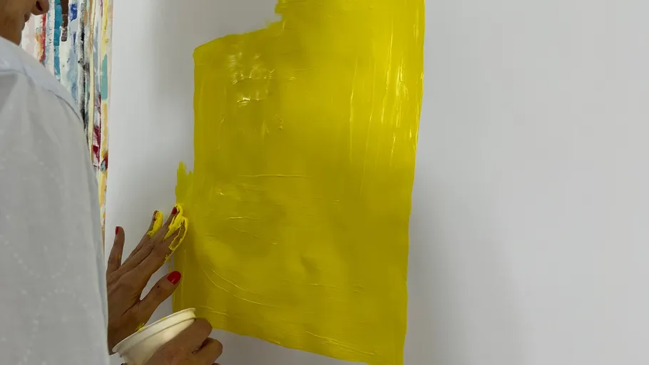 Person painting yellow square on wall.