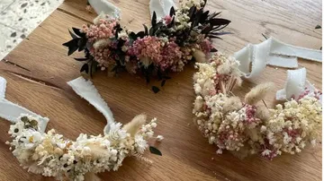 Blumenkränze mit Bändern auf Holztisch.