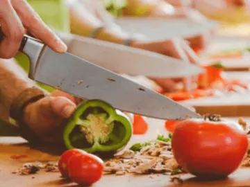 Gemüsemesser schneidet Paprika auf einem Tisch in einer Küche.