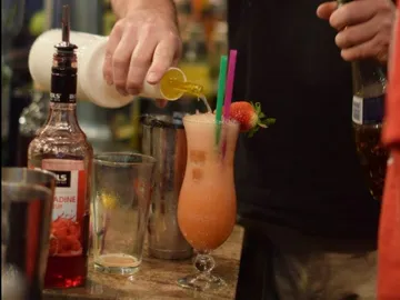 Cocktailglas wird mit einer bunten Flüssigkeit gefüllt.