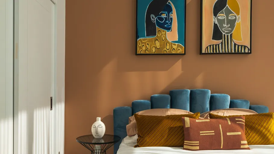 Bedroom with blue headboard, art and pillows.