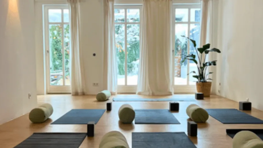 Yoga mats and cushions in sunlit room.