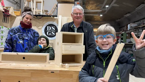 Vier Personen lächeln an einem Holztisch.