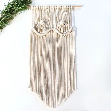 Ein Wandbehang aus Kordel hängt elegant an einer Stange.
