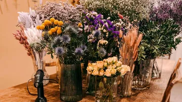Verschiedene Blumen in Vasen auf Holztisch.