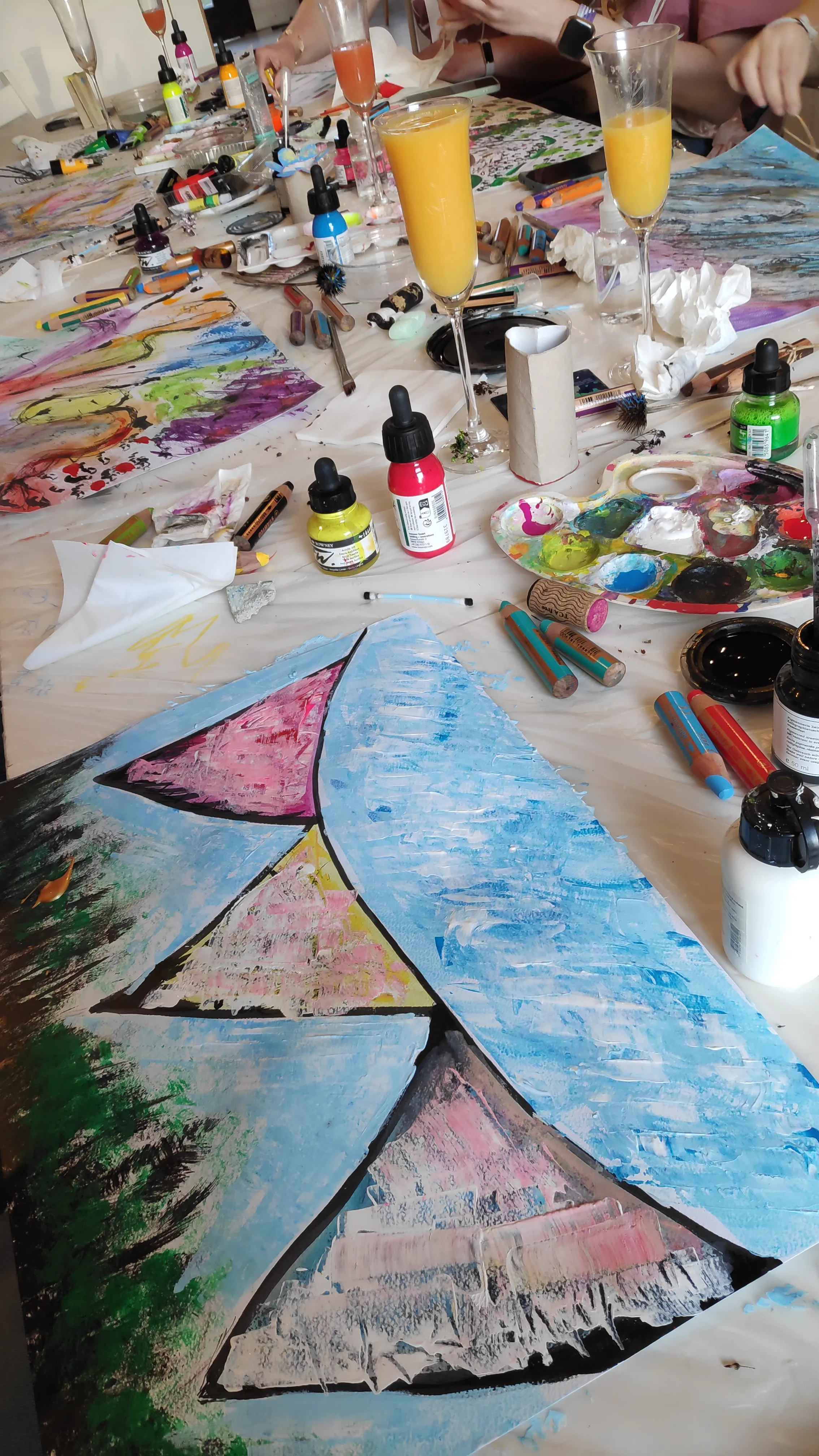 Art supplies and colorful paintings on table.