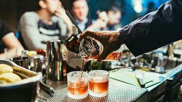 Barkeeper bereitet Cocktails an einer belebten Bar zu.