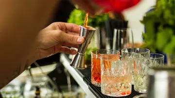 Barkeeper gießt Getränk in Glas an der Bar.