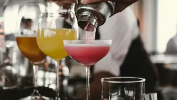 Barkeeper gießt pinken Cocktail ins Glas.